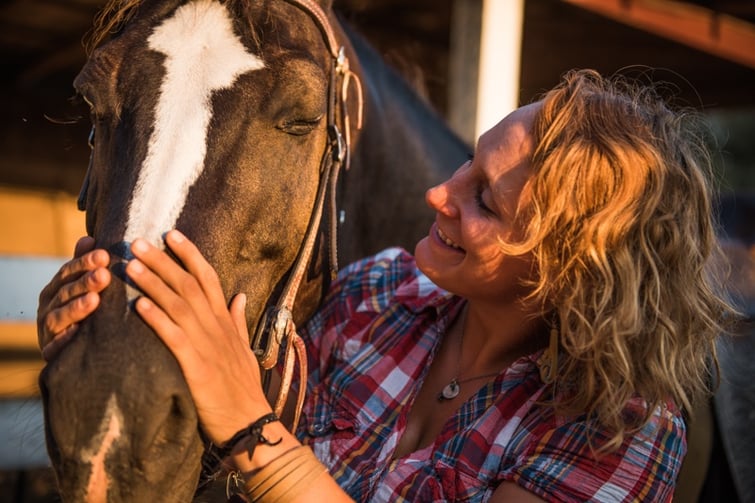 Jamie pets gabe a guarter horse she leads trail rides with on the farm at sunset.jpg