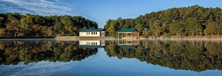 Pond House reflecting in pond water on a sunny day for agroutourism lodging.