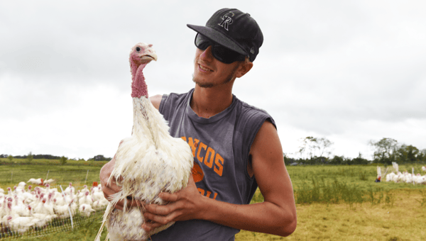 Tre Cates making friends with a pasture raised turkey at White Oak Pastures